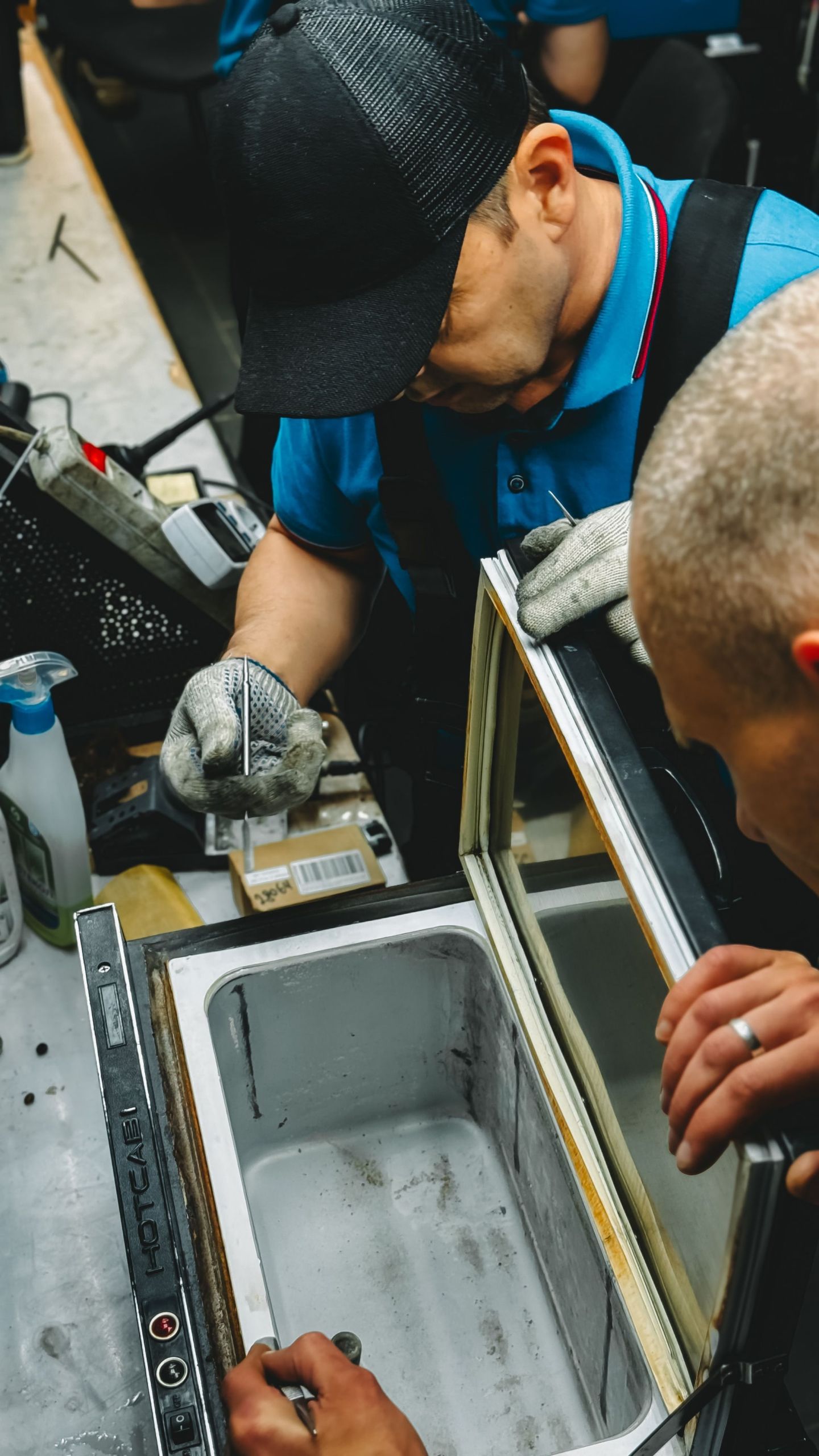 Zwei Techniker mit Handschuhen arbeiten mit Wasserwaage und Werkzeug an einem Edelstahlgerät.